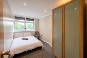 A bedroom with a bed, a window, a wardrobe, and a chair. - Top-Floor 3-Bed Flat Sleeps 6 · Free Parking · Walk to Clissold Park (Greater London)