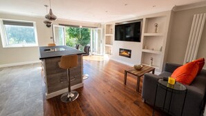 A modern living room with a fireplace, a sofa, and a dining area with a bar. - Top-Floor 3-Bed Flat Sleeps 6 · Free Parking · Walk to Clissold Park (Greater London)