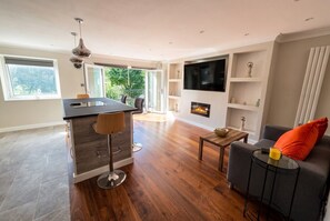 A modern living room with a fireplace, a sofa, and a dining area with a bar. - Top-Floor 3-Bed Flat Sleeps 6 · Free Parking · Walk to Clissold Park (Greater London)