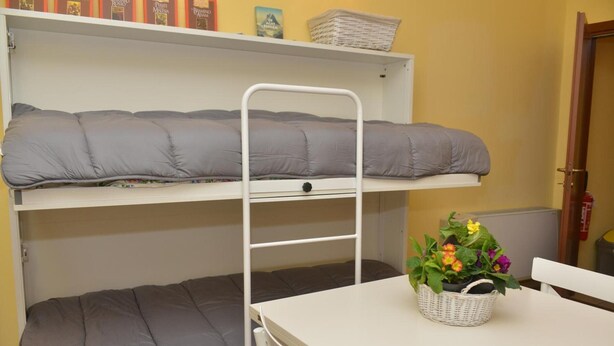 A bunk bed with grey bedding, a white table with a basket of flowers, and a white chair. - Apartment 'Rietinn - Loggia Del Vignola' with Wi-Fi (Rieti)