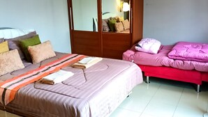 A bedroom with a bed, a bedside table, a mirror, and a wardrobe.