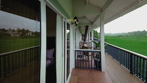 Ein überdachter Balkon mit Blick auf eine grüne Landschaft, ein Stuhl und ein Tisch.