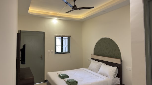 Ein Schlafzimmer mit Bett, Deckenventilator, Fenster und Tür.