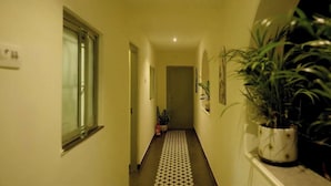 Un pasillo estrecho con piso estampado, una planta en maceta a la derecha y una puerta al final.