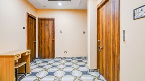Un pasillo con puertas de madera, un escritorio y baldosas de suelo estampadas.