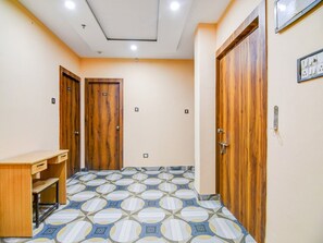 Un pasillo con puertas de madera, un escritorio y baldosas de suelo estampadas.