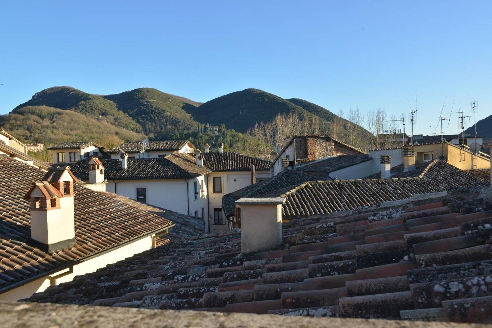A terraced hillside with traditional buildings, some with visible chimneys and satellite dishes.