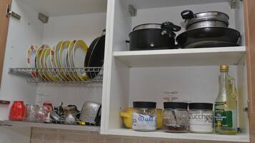 Ein Küchenschrank mit Geschirr, Töpfen und Gewürzen.