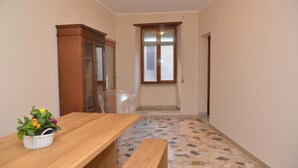 Una stanza con un tavolo in legno, una sedia, un armadio e una finestra con persiane.