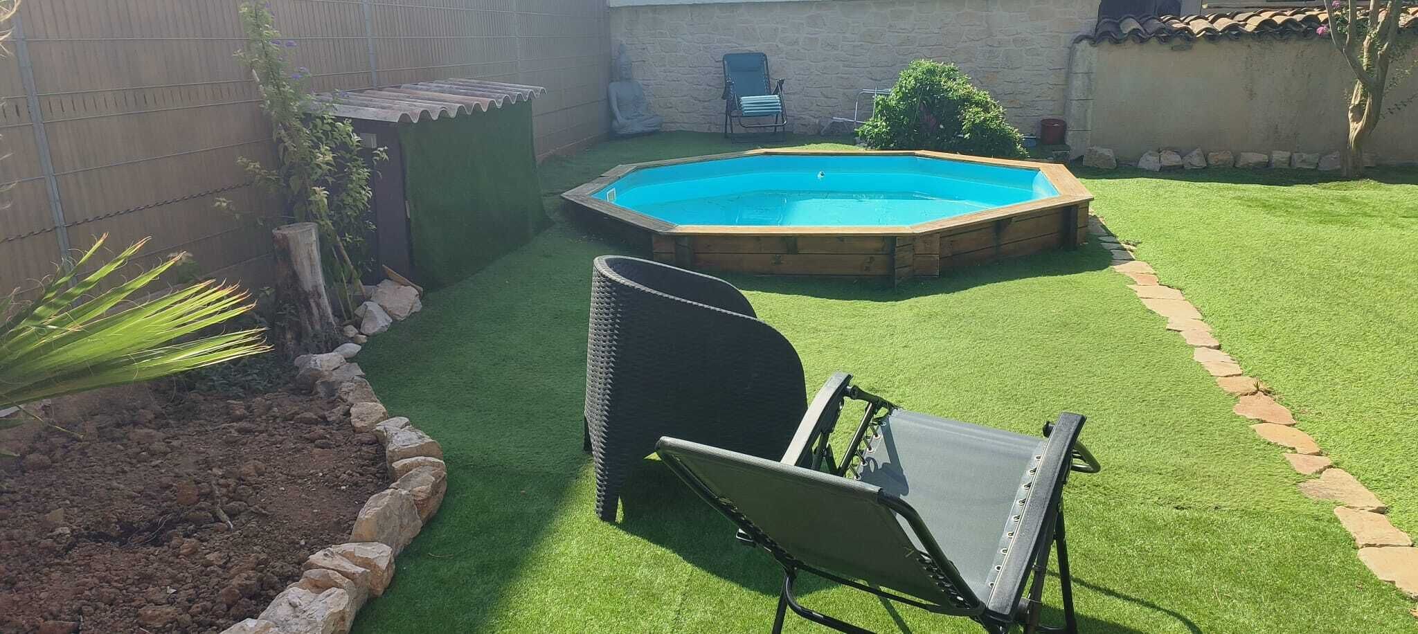 Un jardin avec une pelouse artificielle, une piscine en bois et du mobilier d’extérieur.
