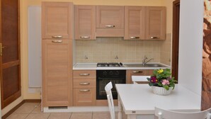 Une cuisine de taille réduite, avec des meubles de rangement en bois, une cuisinière et un évier.