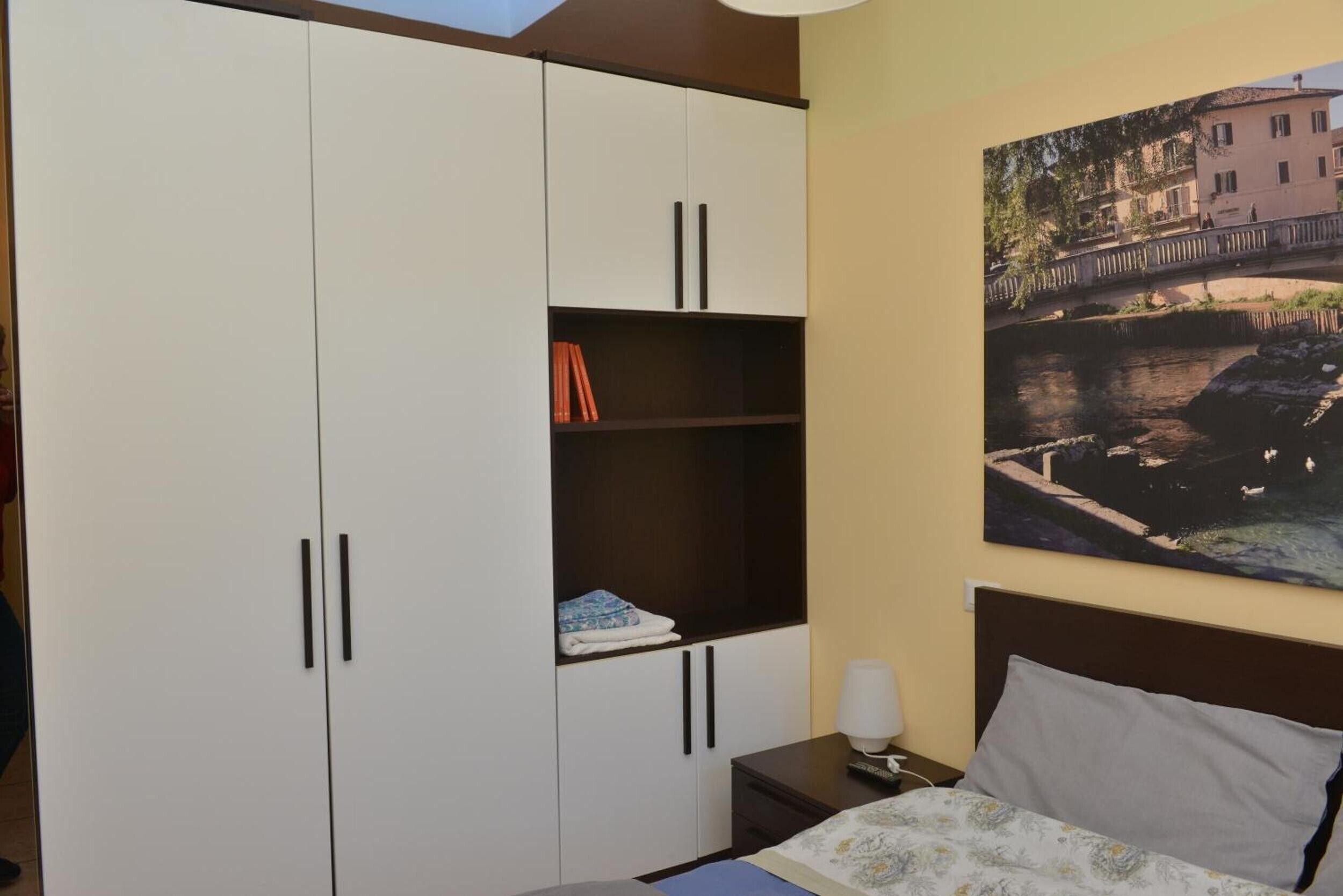 Ein Schlafzimmer mit einem Bett, einem Nachttisch, einem Kleiderschrank und einem Bild an der Wand.