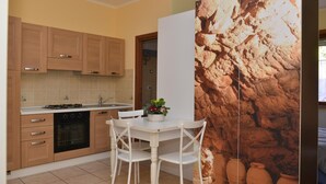 Une cuisine avec des meubles en bois, un plan de travail blanc et un coin repas comprenant une table et des chaises blanches.