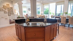 A kitchen with a central island, wooden cabinets, and a tiled floor. - BREATHTAKING : on water front with panoramic views + pool + dock (Dunmore Town)