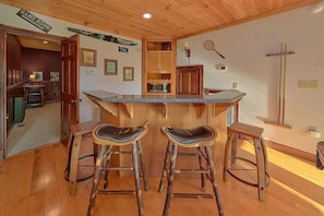 Un área de bar con mostrador de madera, dos taburetes y un microondas.