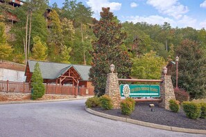 En entré till ett semesterhotell med en skylt som lyder ”Covered Bridge Resort”, omgiven av träd och en byggnad i trä.