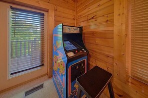 Ein Zimmer mit Holzwänden, einem Fenster mit Jalousien und einem kleinen Tisch.