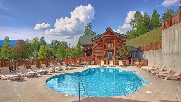 Ein Poolbereich mit Liegestühlen und einer Holzhütte im Hintergrund.