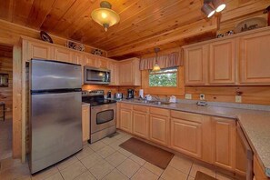 Una cocina con armarios de madera, electrodomésticos de acero inoxidable y un ventanal con vistas.