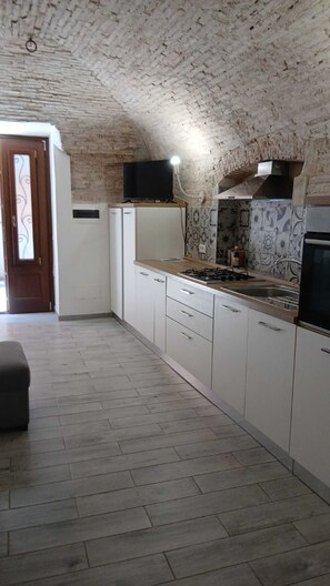 A kitchen with white cabinets, a tiled backsplash, and a built-in stove.