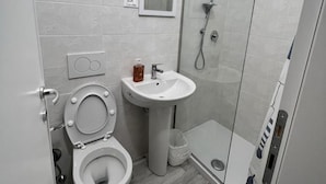 A bathroom with a toilet, sink, and glass shower enclosure.