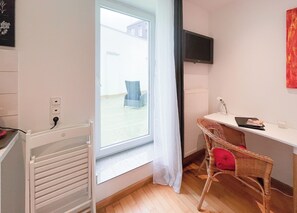 A room with a large window, a radiator, a desk with a chair, and a television on the wall. - Marvelous 1-bedroom apartment in Aachen perfect for your stay (Aachen)