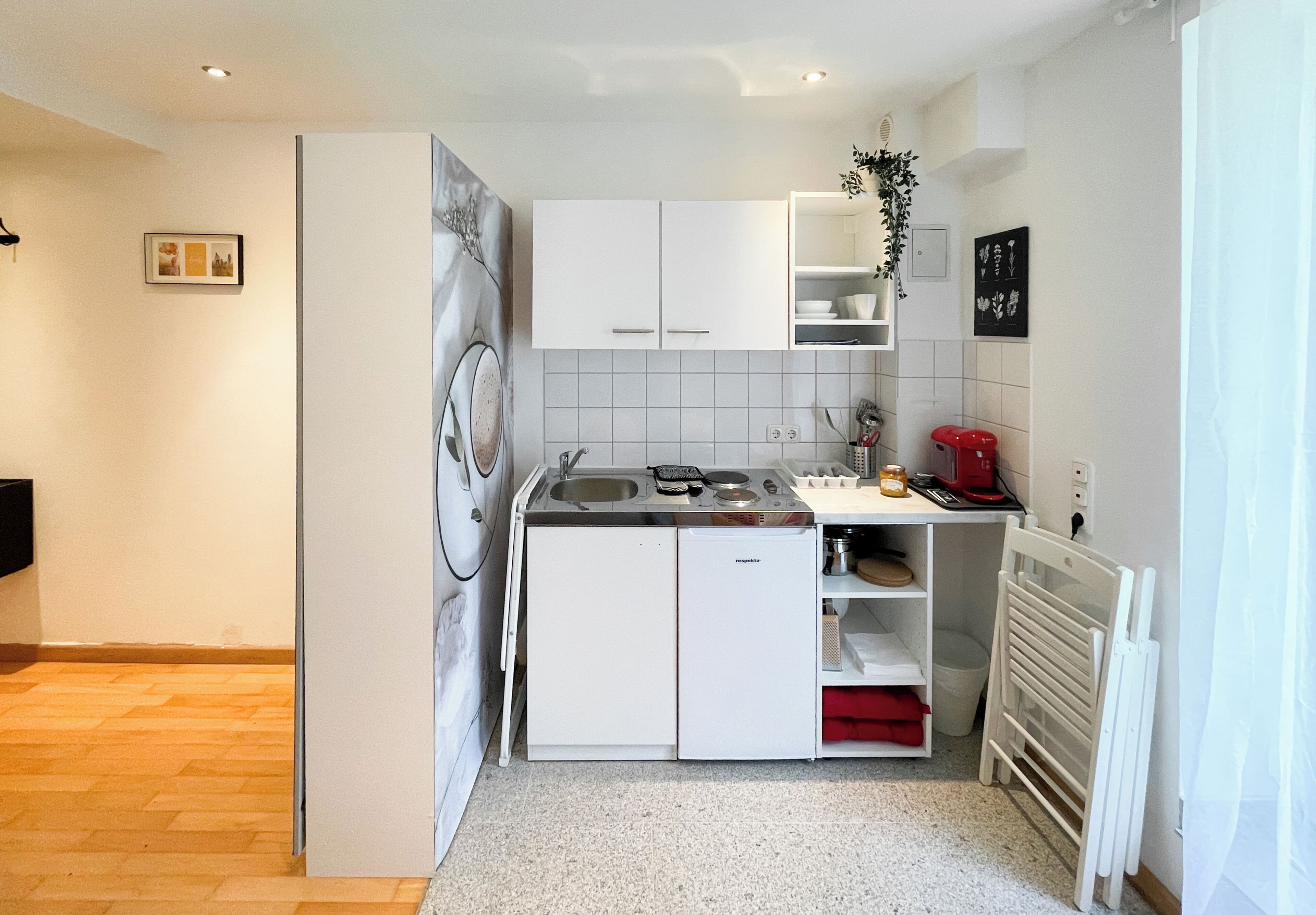 Eine kleine Küche mit weißen Schränken, einem eingebauten Backofen und einem Spülbecken.
