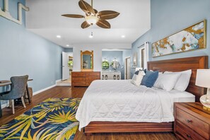 A bedroom with a large bed, wooden headboard, a ceiling fan, a desk, and a chair. - Mauna Kai 7B by Gather | Princeville 3BR + Loft Condo w/ Shared Pool (Princeville)