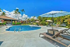 A swimming pool with lounge chairs and umbrellas, surrounded by palm trees and a clear sky. - Mauna Kai 7B by Gather | Princeville 3BR + Loft Condo w/ Shared Pool (Princeville)