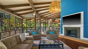 Un amplio salón con chimenea, asientos cómodos y grandes ventanales con vistas a un jardín exuberante.
