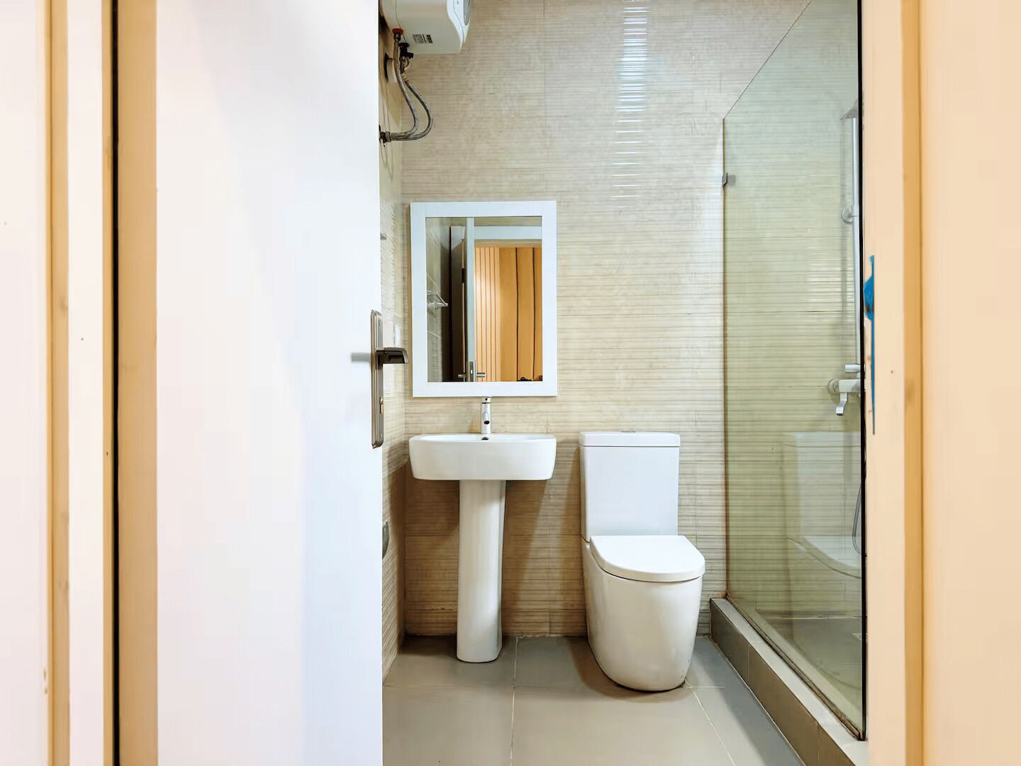 A modern bathroom with a white sink, toilet, and a glass shower enclosure.