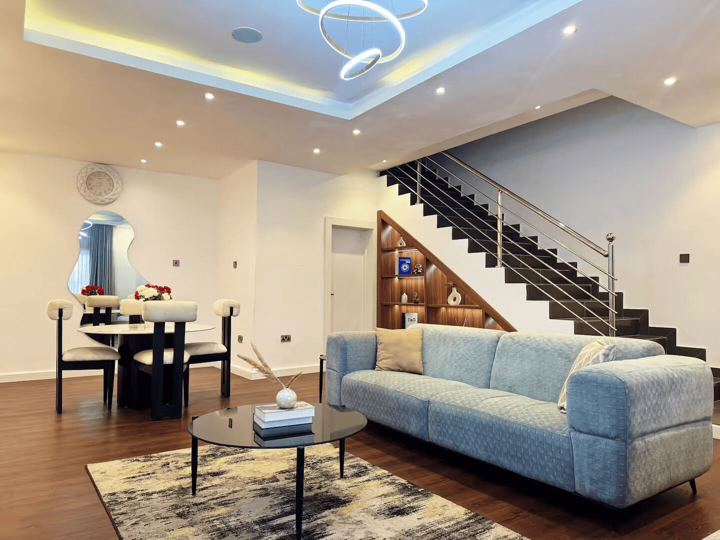 A modern living room with a sofa, coffee table, and a dining area with chairs and a table.