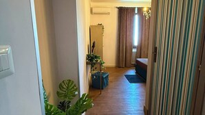 A hallway with a potted plant, a bed, and a striped door. - La Rocca Guest House & SPA - Standard Room 1 (Montefalco)