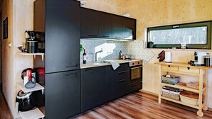 A compact kitchen with dark cabinets, a wooden countertop, and a built-in oven. - Modern cabin by Krøderfjorden near Norefjell (Noresund)