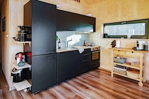 Eine kompakte Küche mit dunklen Schränken, einer Holz Arbeitsplatte und einem eingebauten Backofen.