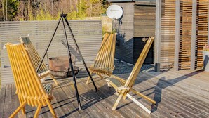 A wooden deck with three wooden chairs and a metal swing set. - Modern cabin by Krøderfjorden near Norefjell (Noresund)