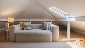 A cozy loft bedroom with a sloped ceiling, a sofa, a lamp, and a skylight. - 2BR Beachside Living by LovelyStay (Costa da Caparica)