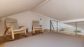 A spacious attic room with two wooden rocking chairs, a small potted plant, and a skylight. - 2BR Beachside Living by LovelyStay (Costa da Caparica)