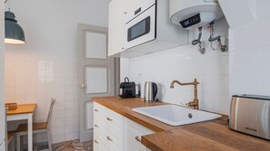 A compact kitchen with a built-in microwave, a coffee maker, and a toaster. - 2BR Beachside Living by LovelyStay (Costa da Caparica)