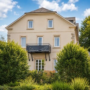 A two-story building with a balcony, surrounded by lush greenery. - Domaine de Pairis (Orbey)