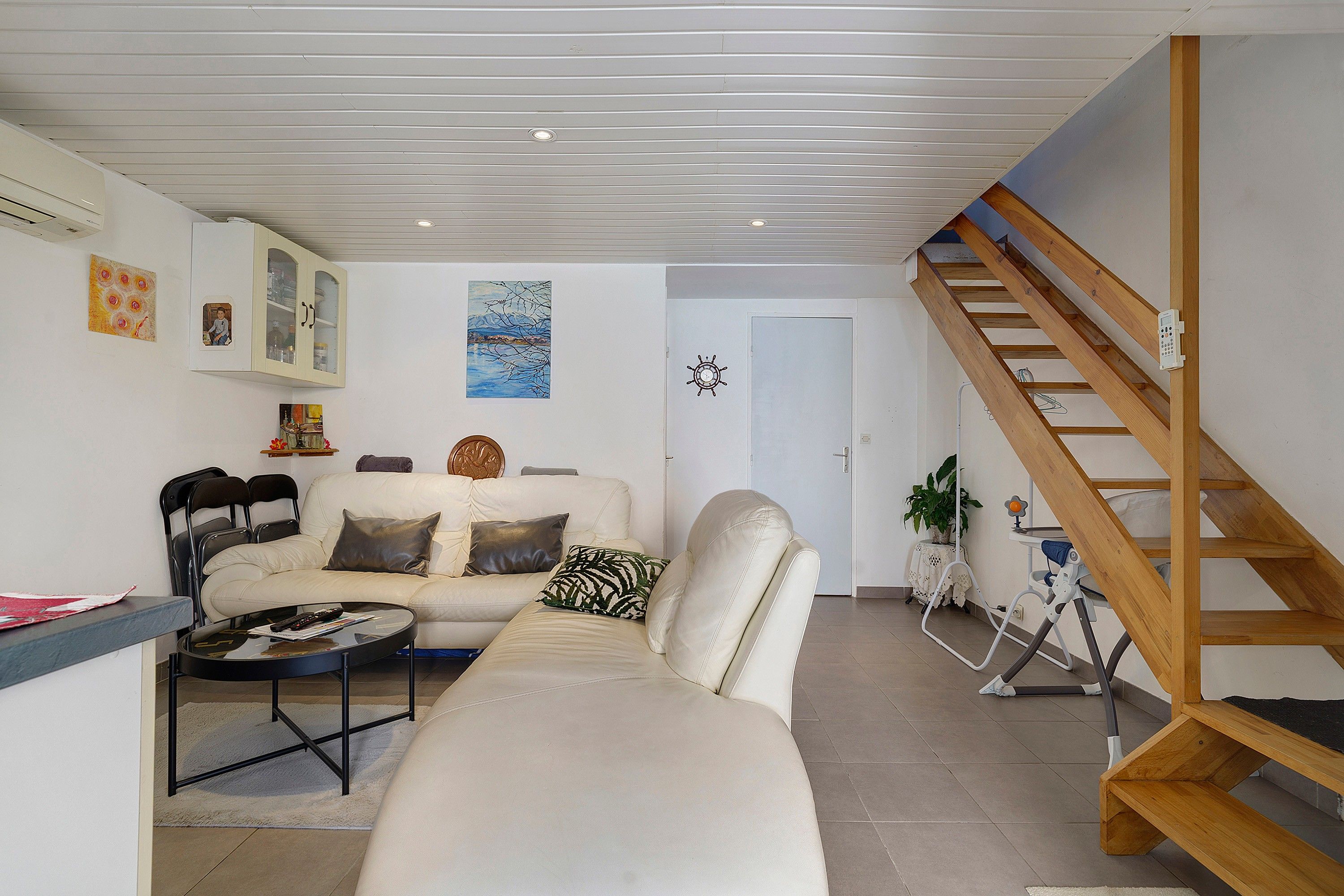 A living room with a sofa, a coffee table, a staircase, and a door.