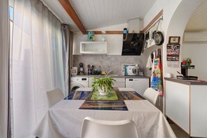 A compact kitchen with a dining area, featuring a washing machine, microwave, and a small refrigerator.