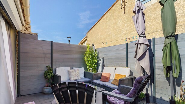 A patio with a wooden deck, outdoor furniture, and a potted plant. - Villa Rosina with Private Terrace, Wi-Fi, and Air Conditioning (Gruissan)
