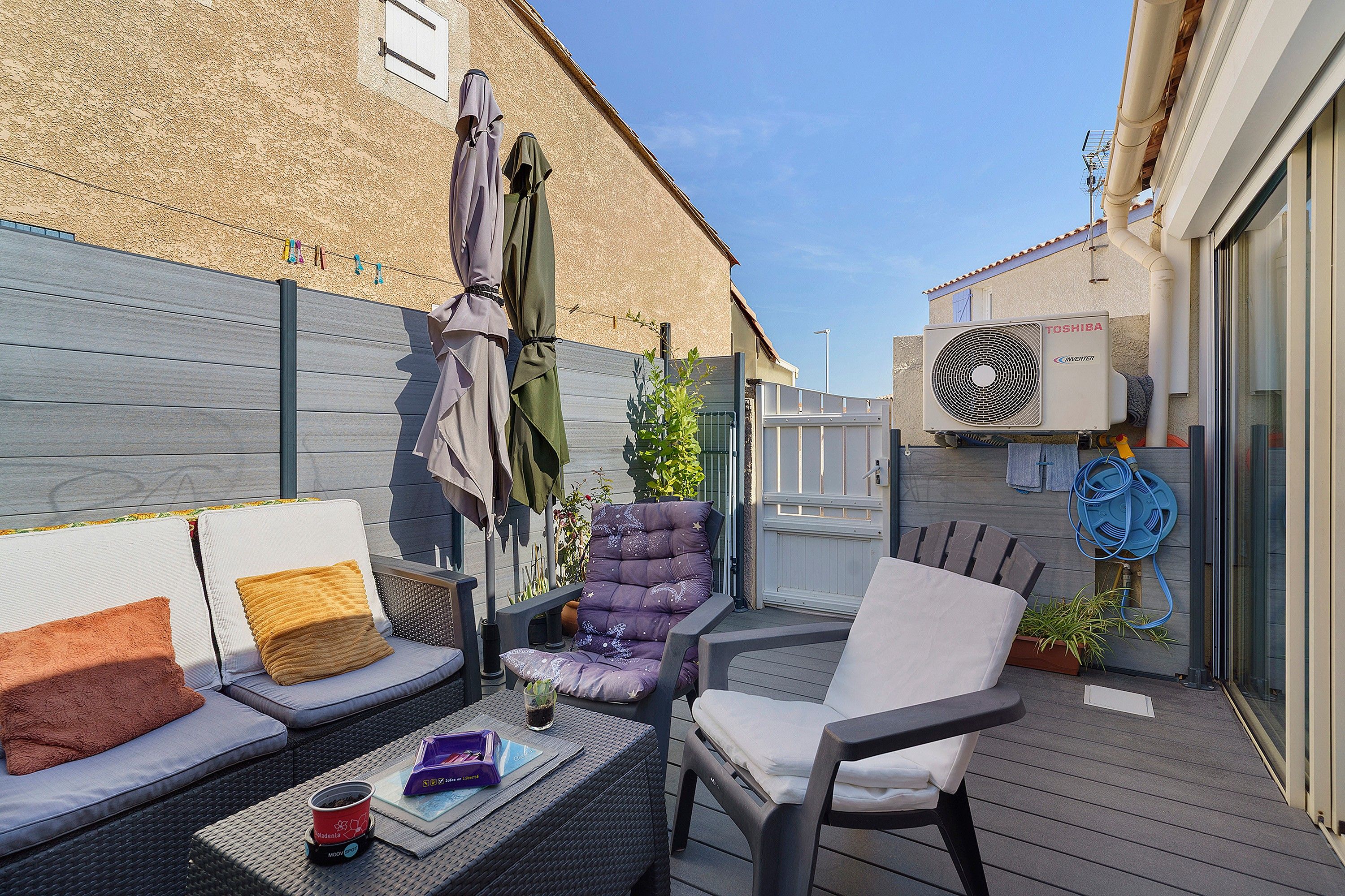 Une terrasse extérieure avec un canapé, des chaises, une table et un chauffe-eau.