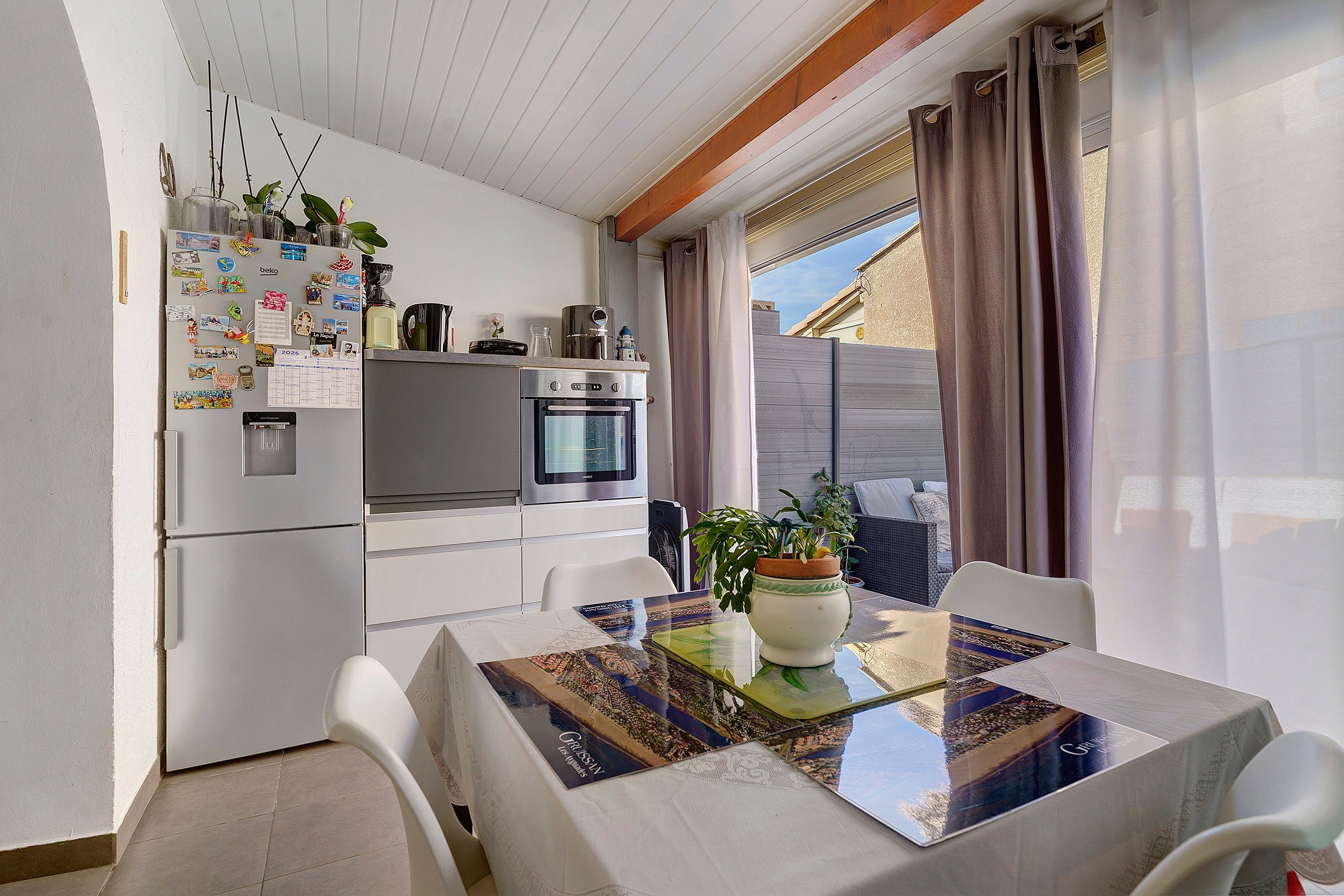 A compact kitchen with a refrigerator, oven, and a dining table with chairs.