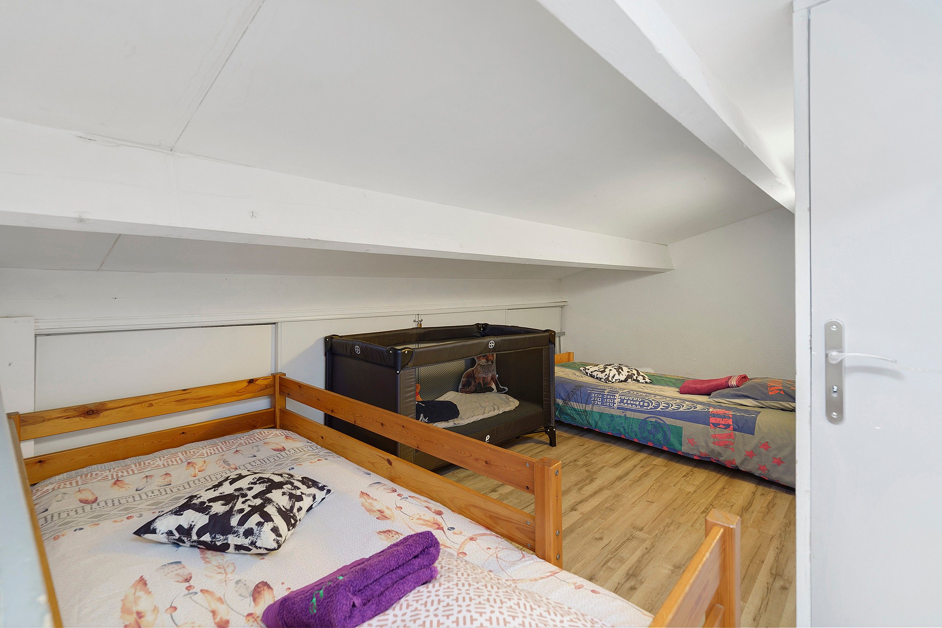 A room with two bunk beds, one with a wooden frame and the other with a metal frame.