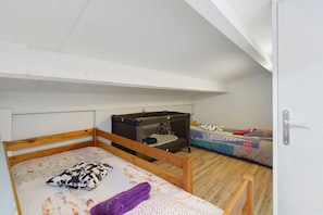 Una habitación con dos literas, una con estructura de madera y la otra de metal.