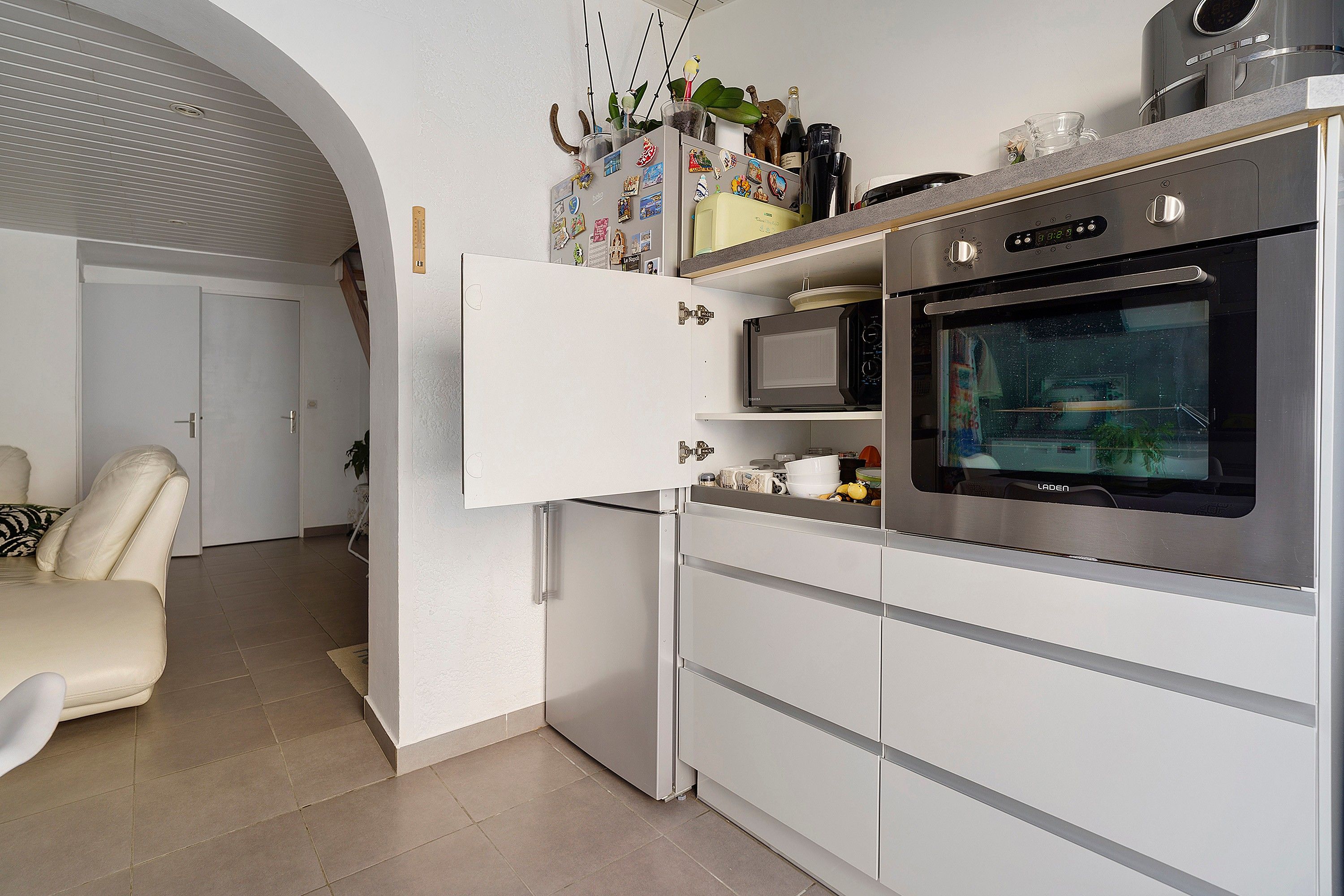 A modern kitchen with a built-in oven, a microwave, and a refrigerator.