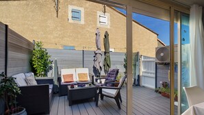 A covered outdoor seating area with wicker furniture, a table, and potted plants. - Villa Rosina with Private Terrace, Wi-Fi, and Air Conditioning (Gruissan)