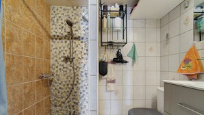 A bathroom with a shower, toilet, and a towel rack with various items. - Villa Rosina with Private Terrace, Wi-Fi, and Air Conditioning (Gruissan)